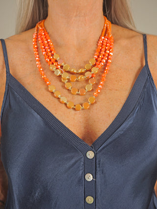 Frau trägt die OFF#DLY 4 Strang Kette orange, ein modisches Schmuckstück aus Glas, um den Hals. Die Kette ist etwa 30 cm lang und betont elegant den Halsbereich.