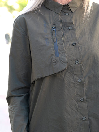 Nahaufnahme der Rundholz Bluse Jungle Print mit Knopfleiste und Brusttasche, sichtbarem Reißverschluss und Faltenstruktur. Modell trägt Größe S, Material aus 100% Baumwolle.