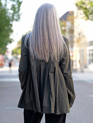 Rundholz Bluse Jungle Print, getragen von einer Frau auf der Straße. Die Bluse hat eine Kopfleiste und Brusttasche, A-Form mit Falten, aus 100% Baumwolle.