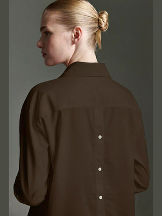 Rückansicht einer Person, die die Cotton Candy Bluse Olivia espresso trägt. Die dunkelbraune Bluse hat lange Ärmel und eine Knopfleiste mit drei weißen Knöpfen am Rücken.