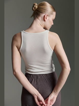 Person von hinten in weißem, ärmellosem Cotton Candy Roca Top, eingesteckt in dunkle Hosen, mit zusammengefassten Händen; schlichtes Design mit Rundhalsausschnitt und breiten Trägern für bequeme Passform.