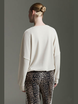 Rückansicht eines Models im Cotton Candy Obdulia Tee offwhite, locker geschnitten mit Rundhalsausschnitt und Bindeband am Saum, kombiniert mit schmalen Leopardenmuster-Hosen.