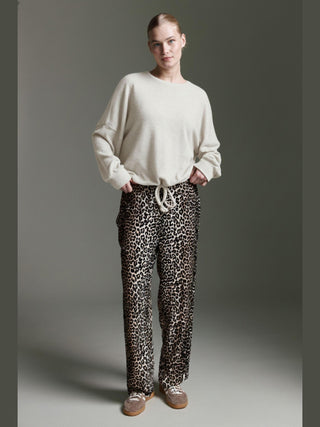 Frau trägt das Cotton Candy Obdulia Tee offwhite, ein locker geschnittenes Longsleeve mit rundem Halsausschnitt, leicht überschnittenen Schultern und Bindeband am Saum, kombiniert mit lässiger Freizeitkleidung.