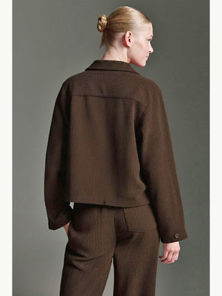 Person von hinten in der Cotton Candy Jacke Mesude espresso, eine kastige, leicht verkürzte Cordjacke mit Umschlagkragen und langen Ärmeln, kombiniert mit passenden, gerade geschnittenen Hosen.