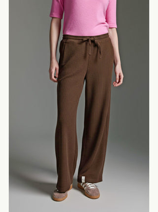 Die Cotton Candy Pant Mehtap espresso zeigt einen weiten, entspannten Schnitt mit elastischem Bund und Tunnelzug, kombiniert mit taupefarbenen Sneakers für einen lässigen Look.