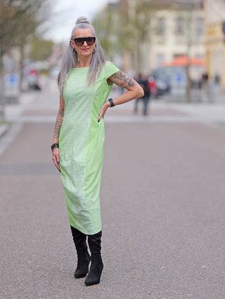 Frau trägt ein Rundholz Kleid 3440904 mit langen Ärmeln. Sie kombiniert es mit großen Sonnenbrillen und schwarzen Stiefeln.