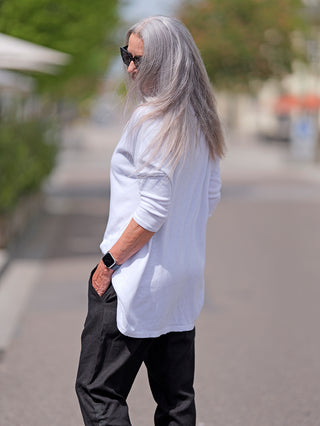 Frau mit langem grauen Haar trägt das OFF#DLY Shirt Elli weiß im Oversized-Look mit Rundhalsausschnitt und 3/4-Ärmeln, ideal für vielseitige, lässige Outfits.