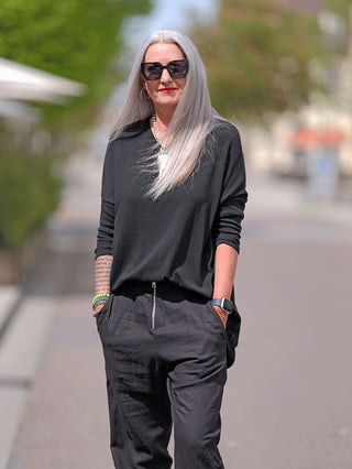 Eine Frau trägt das OFF#DLY Shirt Elli schwarz in einem lässigen, oversized Stil mit Rundhalsausschnitt und 3/4-Ärmeln, kombiniert mit einer locker sitzenden, schwarzen Hose.