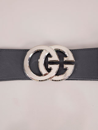 Nahaufnahme des OFF#DLY Gürtel GG schwarz/silber, zeigt eine polierte Metallschnalle mit zwei ineinandergreifenden „G“-Formen auf einem breiten, schwarzen Gürtelriemen aus Leder oder lederähnlichem Material.