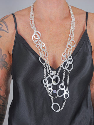 Frau trägt die OFF#DLY Kette Olivia silber, eine dreisträngige, nickelfreie Metallkette von etwa 40 cm Länge. Die Kette liegt elegant um den Hals und betont den modischen Look.