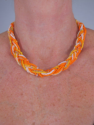 OFF#DLY Flechtkette oange/gelb auf einem Hals, zeigt kunstvoll geflochtenes Design aus Glas und Kunststoff in variabler Länge, betont als modisches Accessoire.