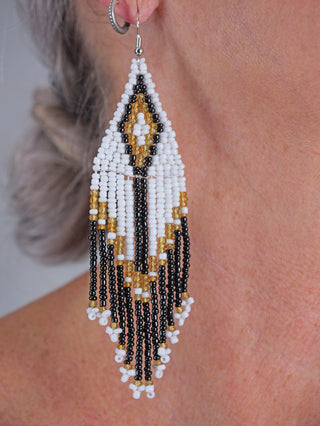 Nahaufnahme des OFF#DLY BoHo Ohrschmucks in schwarz/weiß/gold, bestehend aus Glasperlen mit einer Länge von ca. 11 cm. Ideal als modisches Accessoire und Schmuckstück.