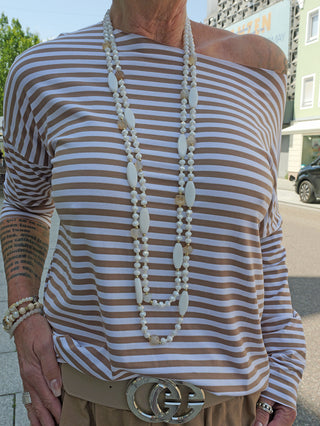 Person trägt eine OFF#DLY Kette Perlen white/beige, bestehend aus zweisträngigen Glasperlen, sichtbar über einem gestreiften Hemd, detailliert um den Halsbereich.