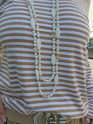 Die OFF#DLY Kette Perlen white/beige wird von einer Person mit gestreiftem Hemd getragen. Die zweisträngige Glasperlenkette hat eine Länge von ca. 55 cm.