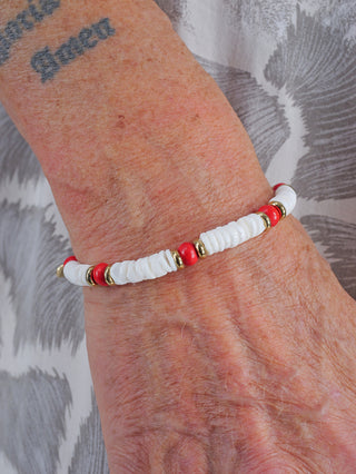 OFF#DLY Armband weiß/rot/gold auf einem Handgelenk getragen, zeigt eine Kombination aus Metall und Tonstein, betont Mode und Stil durch sein einzigartiges Design.