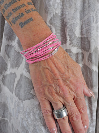 OFF#DLY Monika Armband Set pink: Eine Hand mit rosa und silbernen Armbändern, inklusive Perlenarmbändern, die elegant am Handgelenk getragen werden, sichtbar.