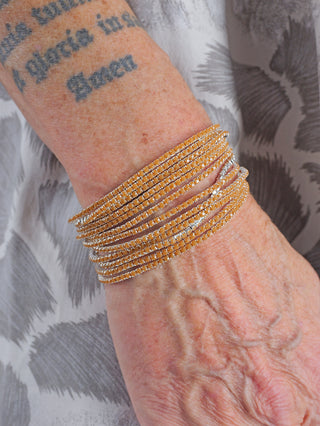 OFF#DLY Monika Armband Set caramel, getragen am Handgelenk. Set aus nickelfreiem Metall und Glas, bestehend aus 12 Armbändern. Sichtbar als modisches Accessoire am Arm einer Person.