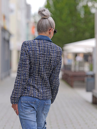 Eine Frau trägt den OFF#DLY Denim Blazer Blue, einen sportlichen Kurzblazer mit schmalem Schnitt und seitlichen Taschen. Sie kombiniert ihn mit blauer Jeans und Sonnenbrille.