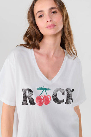 Eine Frau trägt das Indigo Gallery Germany - FAULDI T-Shirt mit lockerem Schnitt und V-Ausschnitt. Es präsentiert einen trendigen Look durch den verwaschenen Stoff und die kurzen Ärmel.