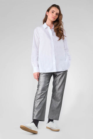 Eine Frau trägt das Shirt Femme Jama mit klassischen Kragen, langen Ärmeln und Knöpfen auf der Rückseite. Das Hemd zeigt ein Ton-in-Ton besticktes Monogramm.