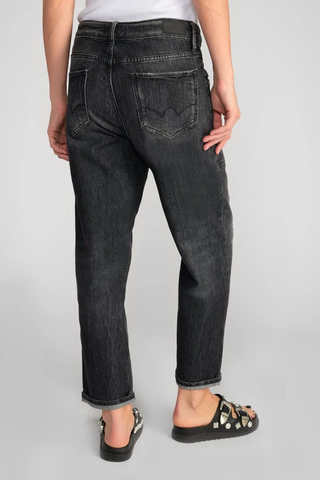 Eine Person trägt die Jean Femme Cosy Pocket mit lockerem Schnitt an Beinen und Knöcheln, erkennbar am originellen asymmetrischen Verschluss und der Tasche hinten.