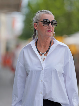 Frau trägt True Religion Bluse Double Cuff Oversized, markant durch Doppelmanschette und großen Kragen, mit Sonnenbrille.