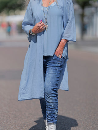 Frau trägt den OFF#DLY Kimono Roxy lightblue, ein leichter Kimono aus 100% Baumwolle, kombiniert mit Jeans. Sichtbares Detail: lange Ärmel und legerer, lässiger Stil.