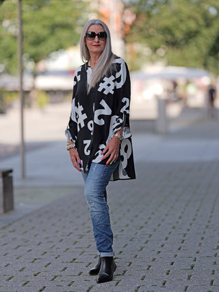 Doris Streich Bluse #7 schwarz-weiß: Frau steht auf Gehweg, trägt lässige Bluse mit Allover-Print, kombiniert mit Jeans und schwarzen Stiefeln. Bluse aus 100% Viskose.