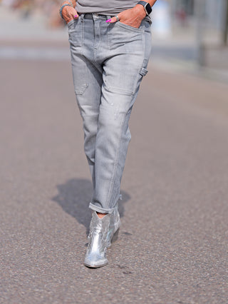 LTC Girlfriend high waist destroy grey Jeans in lockerem Schnitt, getragen mit silbernen Stiefeln. Die Jeans hat eine hohe Taille, gestopfte Löcher und Abrasionen für einen modernen Look.