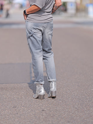 Person trägt LTC Girlfriend high waist destroy grey Jeans mit lockerer Passform und sichtbaren Abrasionen, kombiniert mit silbernen Stiefeln. Jeans hat hohe Taille und gestopfte Löcher.