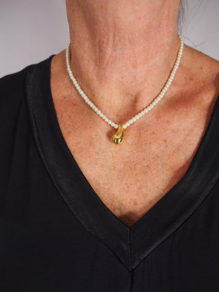 OFF#DLY Kette m. Perlen gold, getragen von einer Person, zeigt eine elegante Kombination aus goldfarbenem Edelstahl und Kunstperlen. Die Kette ist 39 + 5 cm lang und verleiht einen luxuriösen Look.