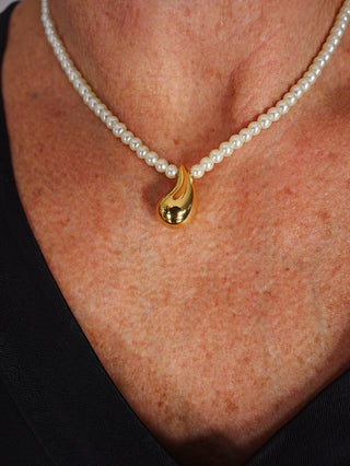 Nahaufnahme der OFF#DLY Kette m. Perlen gold, getragen von einer Person. Die Halskette kombiniert goldene Elemente mit Kunstperlen, ist aus Edelstahl gefertigt und hat eine Länge von 39 + 5 cm.