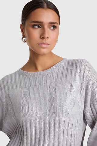 ALIX Foil Pullover champagner, getragen von einer Frau, zeigt ein auffälliges Jacquardmuster auf der Brust und einen ALIX-Aufnäher am Ärmel, mit rundem Halsausschnitt und langen Ärmeln.