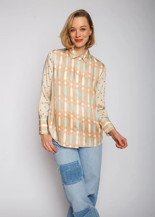 Emily Bluse 796 sand/blue: Frau trägt lässige Hemdbluse mit geometrischem Muster, langen Ärmeln und Manschetten, kombiniert mit blauen Jeans. Viskose Satin-Material verleiht der Bluse einen fließenden Look.