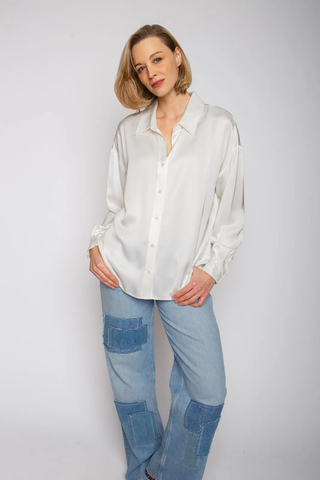 Emily Bluse 102 offwhite, getragen von einer Frau. Die Bluse ist oversized mit überschnittener Schulter und Knopfblende. Sie hat eine lässige Mehrweite durch Falte im Rückenteil.