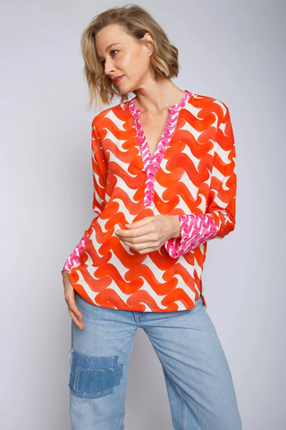 Emily Bluse 490 in einem fließenden Stoff mit V-Ausschnitt, kleinem Kragen und langen Ärmeln. Das Modell trägt eine leuchtende Bordüren-Print-Bluse aus 100% Viskose.