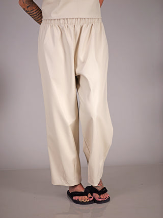 Person trägt MAT Hose 2074 creme, eine Fake-Leder-Culotte aus Viskose mit Gummibund, kombiniert mit schwarzen Sandalen.