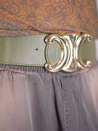Nahaufnahme des Gürtel CC Groß grün mit goldfarbener Schließe. Der elastische Taillengürtel besteht aus Polyester und Metall, ideal zum Abrunden von Outfits.