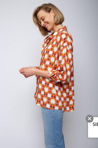 Emily Bluse 890 multi/geo: Frau trägt lässige, oversized Hemdbluse mit überschnittener Schulter und multicolor Grafik-Print. Die Bluse hat eine Knopfblende und Rückenteilfalte für Mehrweite.