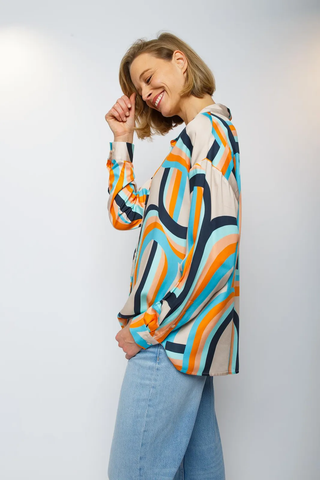 Emily Bluse 791 orange/sand: Frau lächelt, trägt eine Shirtbluse mit Stehkragen, V-Ausschnitt, schmalen Manschetten. Geometrischer Print, lässiger Schnitt, ideal für einen modernen Look.