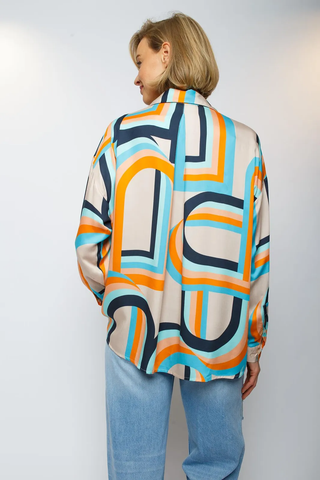 Emily Bluse 791 orange/sand: Frau trägt bunte Shirtbluse mit Stehkragen, V-Ausschnitt, schmalen Manschetten und modernem geometrischen Print. Leichte Weite durch Falte in der Mitte.