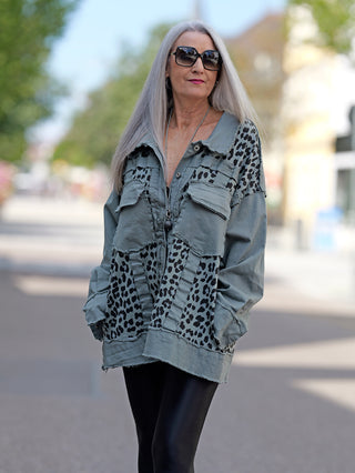 Eine Frau trägt die OFF#DLY Jacke Celia khaki, eine oversized Jacke mit Leopardenmuster und großen Brusttaschen, während sie auf der Straße steht und Sonnenbrillen trägt.