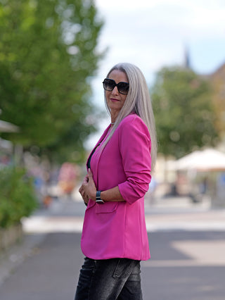 Frau trägt den OFF#DLY Blazer Pamela Pink mit 3/4-Ärmeln, schmal geschnitten, ohne Futter, kombiniert mit Sonnenbrille. Ideal für modischen Streetstyle, passend bis Größe 38.