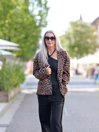 Eine Frau trägt den OFF#DLY Leoblazer Rita, einen modischen, kurz geschnittenen Leopard-Jacke mit Schulterpolstern und seitlichen Taschen, kombiniert mit Sonnenbrille.
