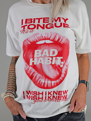 Frau trägt das OFF#DLY Tee I BITE, ein weißes T-Shirt mit rotem Lippen- und Textdruck, Rundhals und kurzen Ärmeln. Material: 95% Baumwolle, 5% Elastan.
