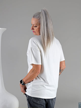 Frau mit grauem Haar trägt OFF#DLY Tee I BITE, ein T-Shirt mit Rundhals und rotem Print. Eine Smartwatch sichtbar an ihrem Handgelenk.