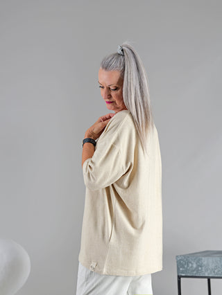 Eine Frau mit langen grauen Haaren trägt das Cotton Candy Tee Umut, ein weiches, lässiges Langarmshirt mit O-Neck Ausschnitt. Ein schwarzes Armband ist an ihrem Handgelenk sichtbar.