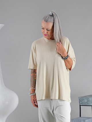Frau mit tätowiertem Arm trägt das Cotton Candy Tee Umut, ein weiches, lässiges Langarmshirt mit O-Neck, ideal für Komfort und Stil. Sichtbares Accessoire: eine Uhr am Handgelenk.