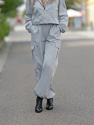 Person trägt den OFF#DLY Anzug Tina grey mit sportlicher Jacke und Hose. Der Anzug hat Cargotaschen, elastische Bündchen an Jacke und Hose, und einen verstellbaren Beinabschluss.