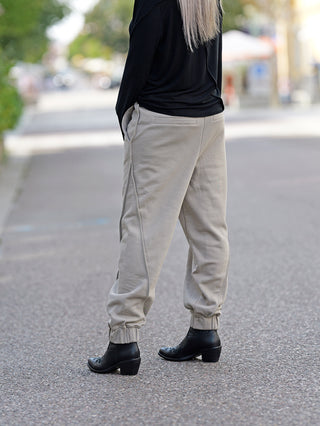 ThomKrom WST 384 Pant, getragen von einer Person mit schwarzen Boots. Lässige Sweathose mit elastischem Bündchen, Paspel-Details, gefertigt aus weicher Baumwoll-Sweat-Qualität.